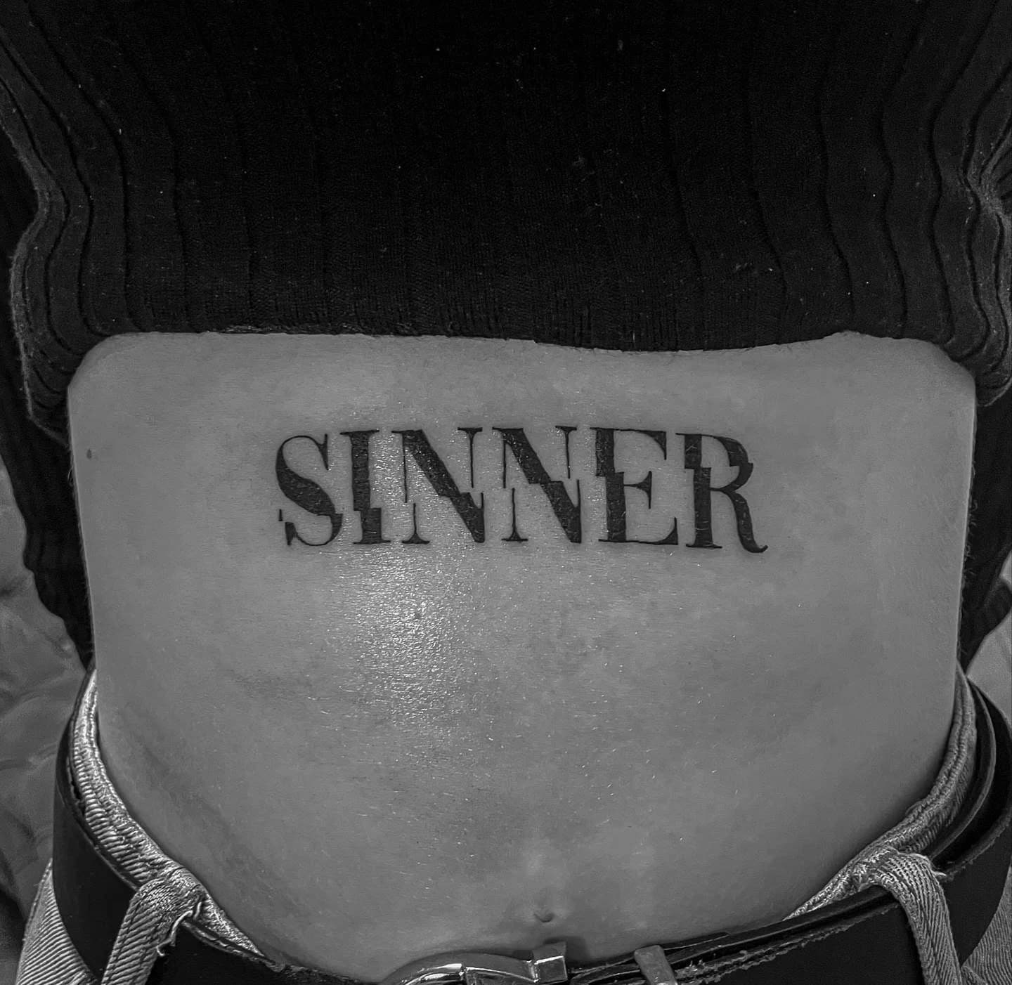 Geradliniger Sinner-Schriftzug über dem Bauch